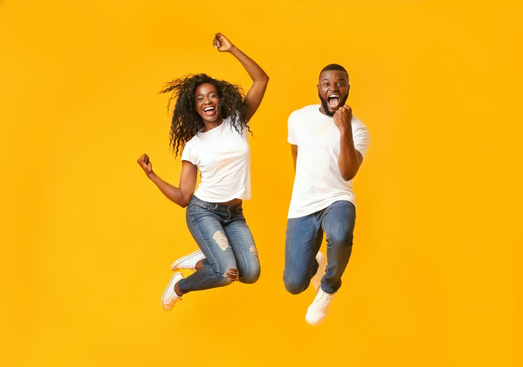 Joyful black couple jumping up and down